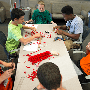 Group of yound students work with pipe cleaners during camp